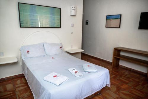 a bedroom with a white bed with towels on it at Bungalows Las Arenas in San Patricio Melaque
