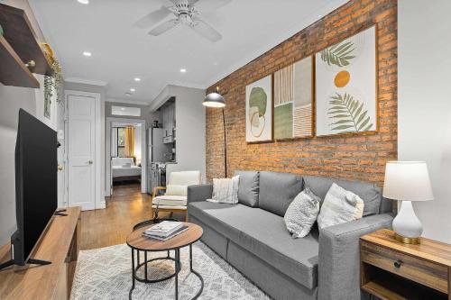 a living room with a couch and a brick wall at Stylish Escape in the East Village in New York