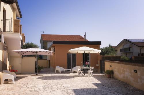 Un patio con mesas, sillas y sombrillas. en Villa MARTINA, en Ortona