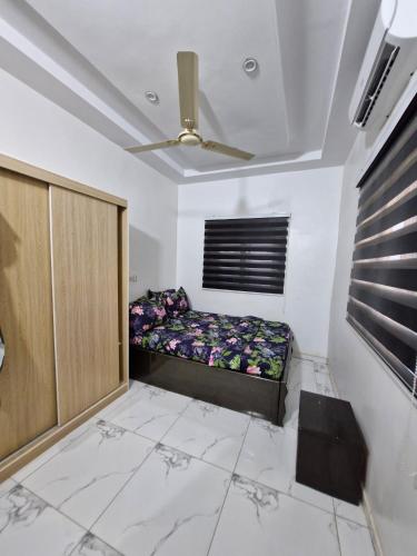 a room with a bed and a ceiling fan at Séjour Élégant à Agoè in Komé