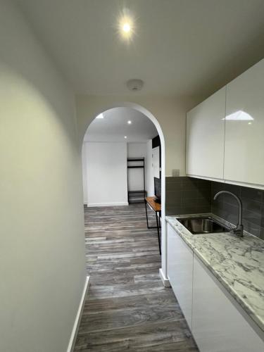 eine Küche mit weißen Schränken und einer Spüle und einem Flur in der Unterkunft Yugogo One-Bedroom Apartment 37 London Road in St Albans