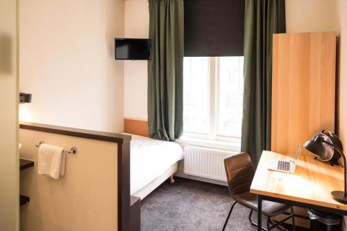 a hotel room with a bed and a desk and a window at Bovendonk Business- & Eventlocatie Hoeven in Hoeven