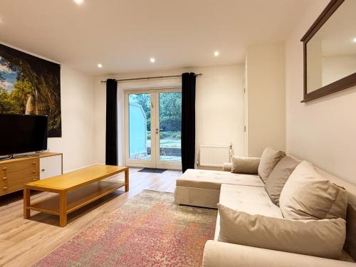 a living room with a couch and a tv at Laura's modern 1 bed apartment in Wimbledon in Merton