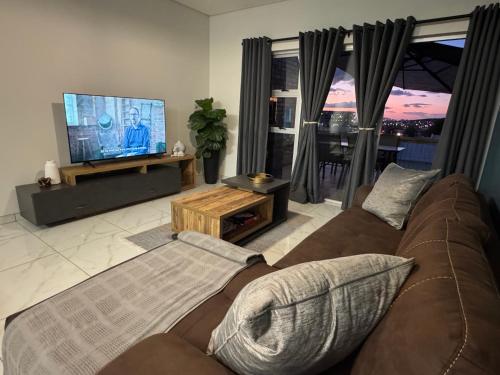 a living room with a couch and a flat screen tv at Weavers Nest 34 in Windhoek