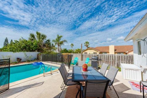 Un patio con mesa y sillas junto a una piscina. en Large pool home & blocks away from the beach, en Daytona Beach