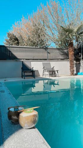une piscine avec deux chaises et une table dans l'établissement Le soleil de pessac, à Pessac