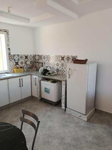 a kitchen with a refrigerator and a table and a chair at Dar Marhaba bis karkouane in Kerkouene