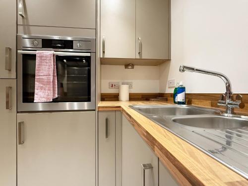 a kitchen with a sink and a microwave at Laura's modern 1 bed apartment in Wimbledon in Merton