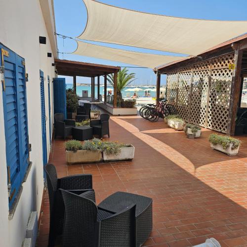 a patio with black chairs and tables on a building at Vel Marì - Rooms on the Beach in Alghero