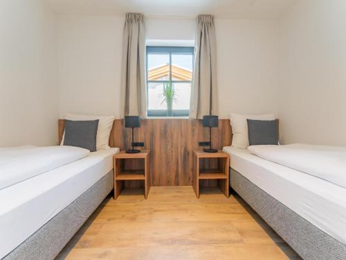 twee bedden in een kamer met een raam bij Tauernlodge Eben A3 in Eben im Pongau