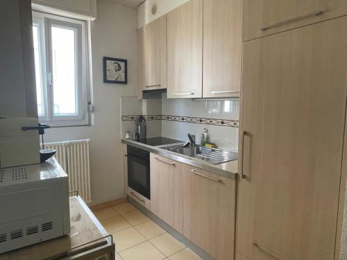 a kitchen with wooden cabinets and a sink and a window at Appartement clame 6 minutes de la gare de Lausanne in Lausanne