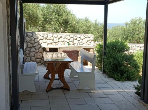 a table and chairs on a patio with a stone wall at Holiday Home Ruby in Sveti Jakov