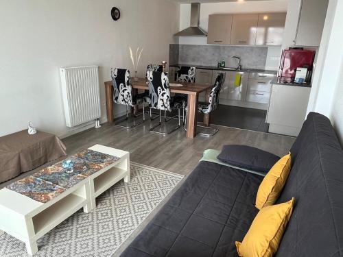 un salon avec un canapé et une table et une cuisine dans l'établissement Charmant T3 avec balcon et parking, à Strasbourg