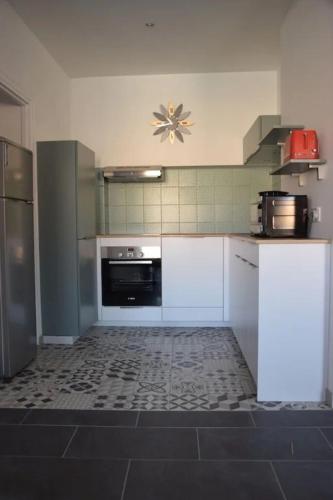 une cuisine avec des armoires blanches et un four noir dans l'établissement La belle douanière, à Port-Vendres