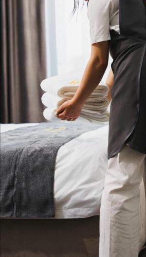 a woman standing next to a bed with a stack of pillows at Sim Plaza Hotel in Ejmiatsin