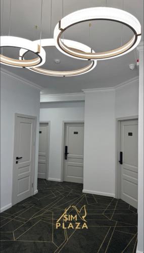 a hallway with three doors and a chandelier at Sim Plaza Hotel in Ejmiatsin