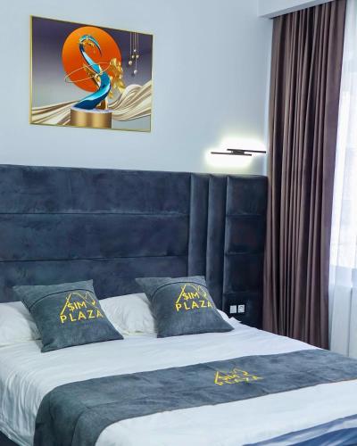 a bedroom with a bed with a blue head board at Sim Plaza Hotel in Ejmiatsin