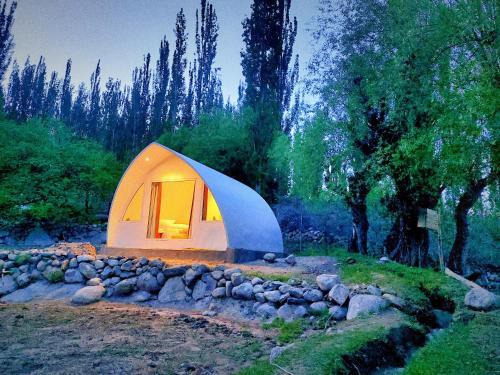 una piccola tenda bianca in un campo alberato di Belle Epoque Mountain Resort, Hunza, Gilgit Baltistan a Valle dell'Hunza