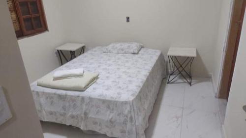 a bed in a white room with two tables at Pousada da Prata in Águas da Prata