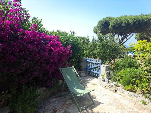 a green chair sitting next to a fence and purple flowers at La Pointe de Sel - Plage a 2 minutes a pied in Lumio