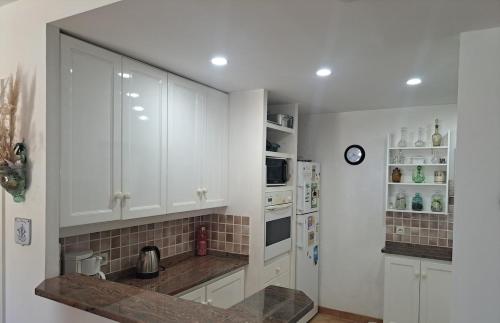 une cuisine avec des armoires blanches et un réfrigérateur blanc dans l'établissement La Pointe de Sel - Plage a 2 minutes a pied, à Lumio