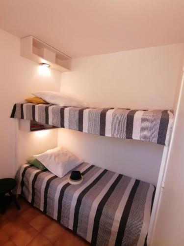deux lits superposés dans une chambre avec un chapeau sur un lit dans l'établissement La Pointe de Sel - Plage a 2 minutes a pied, à Lumio