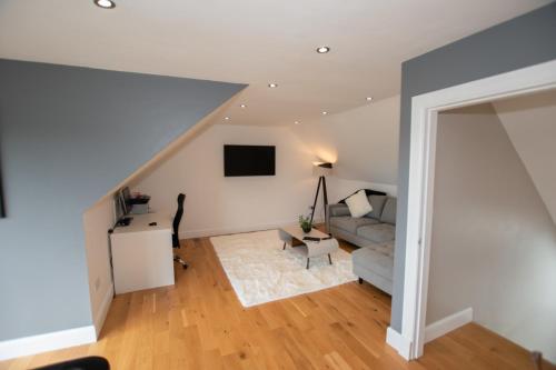 a living room with a couch and a tv at Penthouse at the White House near Edinburgh in Bathgate