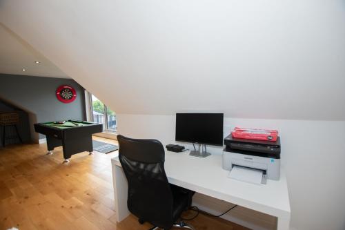 a living room with a desk with a television and a computer at Penthouse at the White House near Edinburgh in Bathgate