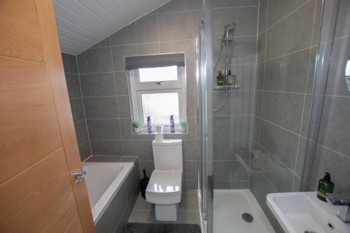a bathroom with a toilet and a tub and a sink at Penthouse at the White House near Edinburgh in Bathgate