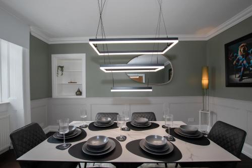 a dining room with a table with chairs and aandelier at Penthouse at the White House near Edinburgh in Bathgate