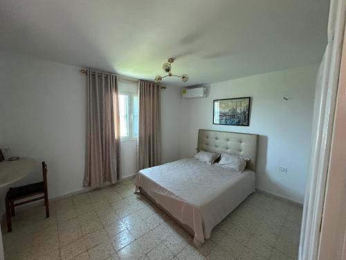 a bedroom with a bed and a table and a window at DAR AZAIEZ El Haouaria Villa 4 Chambres climatisé belle piscine in El Haouaria