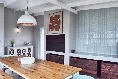 a dining room with a wooden table and a television at Palm Villa Beachfront Accomodation in Hentiesbaai