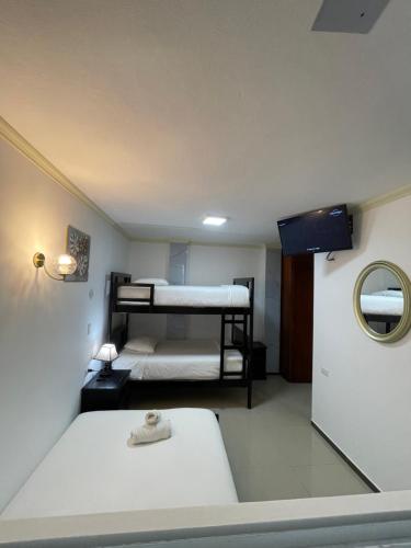 two beds in a small room with a mirror at Hostal Balcon del Cielo in Baños
