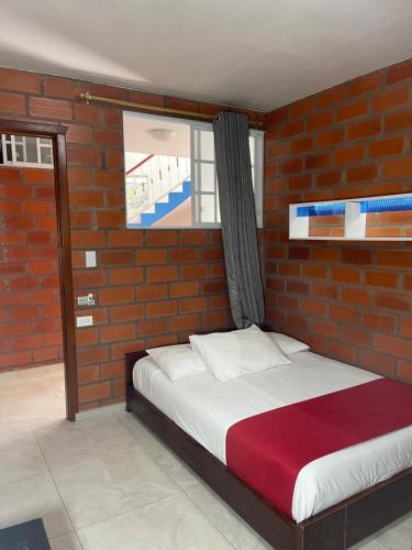 a bedroom with a brick wall with a bed at Hostal Balcon del Cielo in Baños