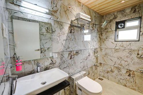 a bathroom with a white sink and a toilet at The leaf resort Mahabaleshwar in Mahabaleshwar