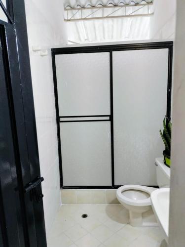a bathroom with a white toilet and a black door at El Podio, casa quinta vacacional Ricaurte in Ricaurte