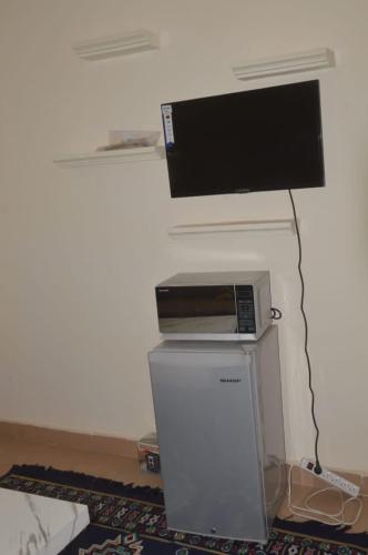 a television on a wall with a small refrigerator at Torobali IMMO Studio 1 -Cozy Furnished Studio - City Center Bamako- Ideal for short Stays in Bamako