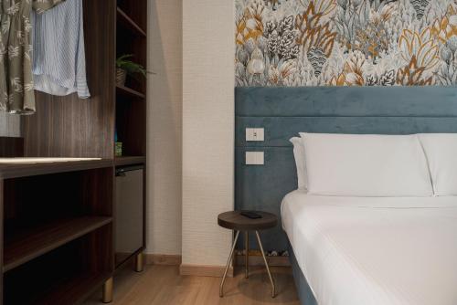 a bedroom with a white bed and a stool next to a bed gmaxwell gmaxwell gmaxwell at Hotel Grazia Riccione in Riccione