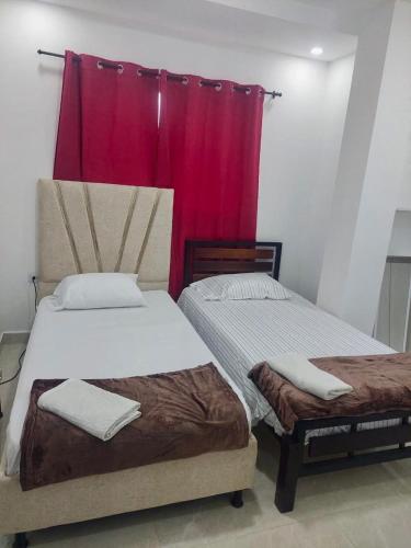 two beds in a room with a red curtain at Perla del río habitaciones in Barranquilla