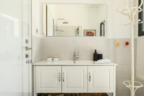 a white bathroom with a sink and a mirror at Aliyah - Country Garden Apartment in Matta‘