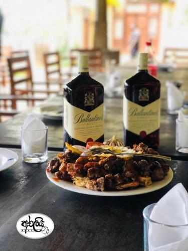 twee flessen alcohol en een bord met eten op een tafel bij Araliya Villa in Balapitiya