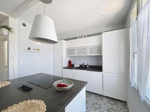 une cuisine avec des armoires blanches et un comptoir noir dans l'établissement Appartement de charme Erdizka classé 3 étoiles, à Bayonne