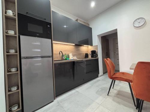 a kitchen with a refrigerator and a table and a clock at Apartament A - Rynek 4, Pasym in Pasym