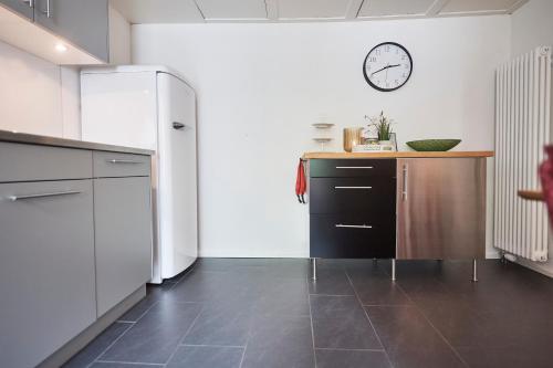 a kitchen with a refrigerator and a clock on the wall at fabrikzeit-bijou-glarus - Blick auf Berge in Glarus