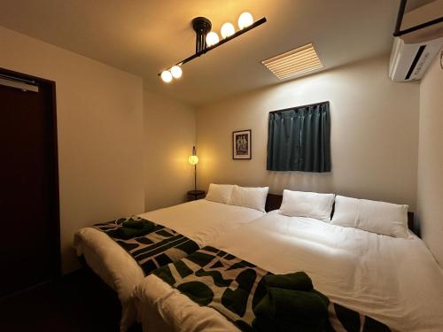 a bedroom with two white beds and a window at 北渋谷inn in Tokyo