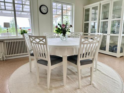 a white dining room table with chairs and a vase of flowers at Sörbygården Bed & Breakfast in Brunflo