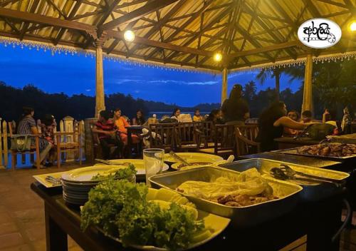 a table topped with plates of food on a table with people at Araliya Villa in Balapitiya