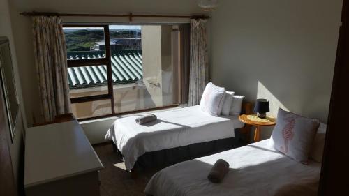 Una habitación de hotel con dos camas y una ventana. en Oyster Catcher Stay And Explore, en Cape St. Francis