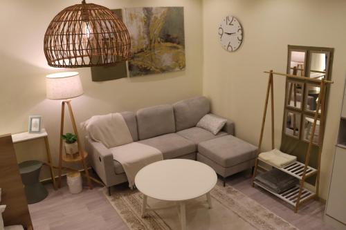 a living room with a couch and a table and a clock at Olive Studio Madinah- Elegant KingBed Studio in Al Madinah