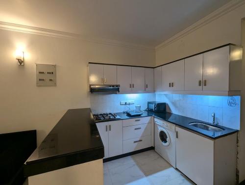 una cucina con mobili bianchi e lavatrice di 2BHK Flat in Arpora, 10 mins from Baga Beach ad Arpora